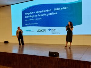 Maike Mülders von contec und Nadine Reussel-Distler von der Diakonie Baden stehen auf der Bühne bei der 6. KoBrA-Konferenz.