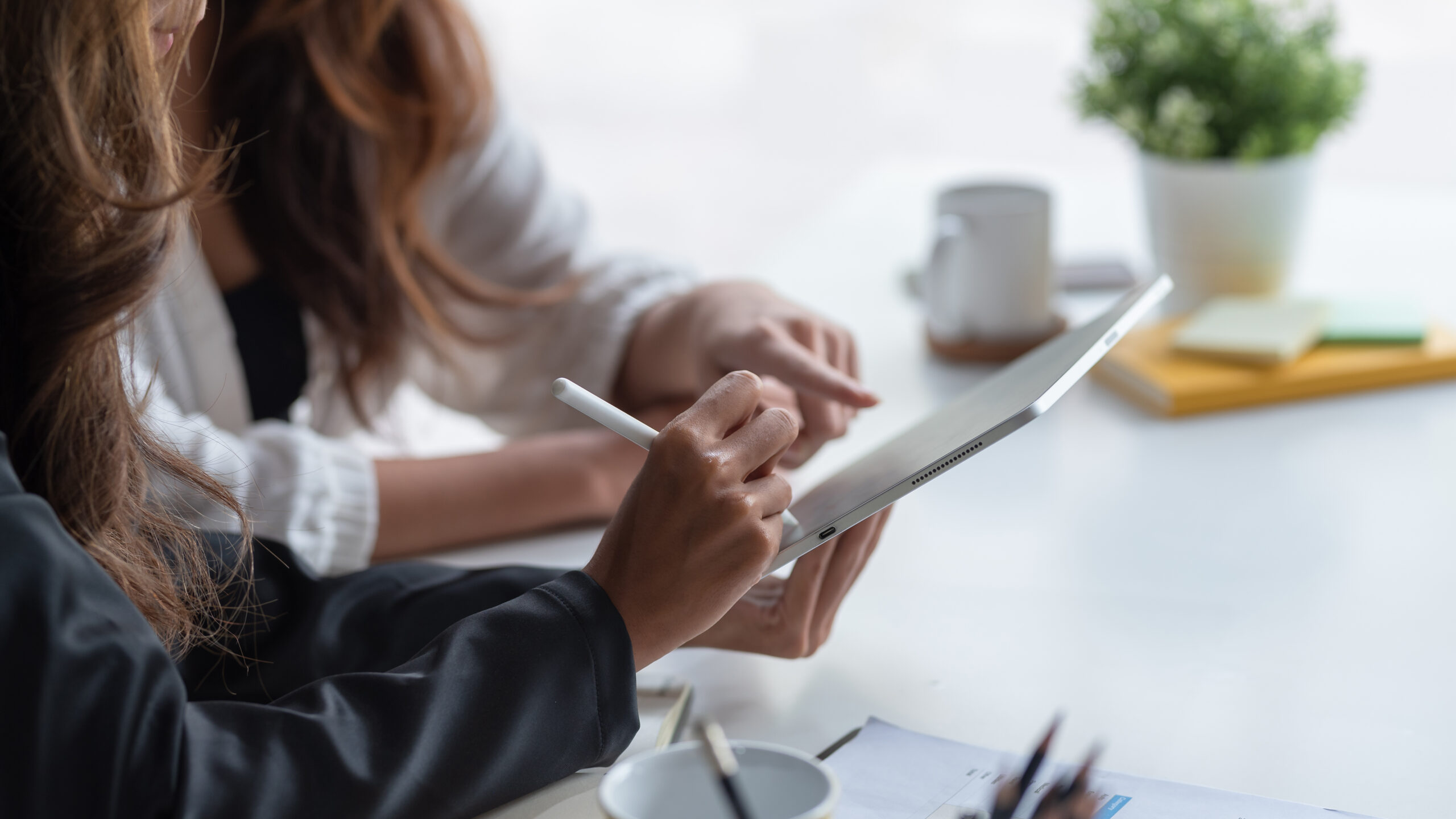 PeBeM-Modellprogramm. Auf dem Bild sieht man zwei Frauen, die gemeinsam an einem Tablet etwas planen und diskutieren.